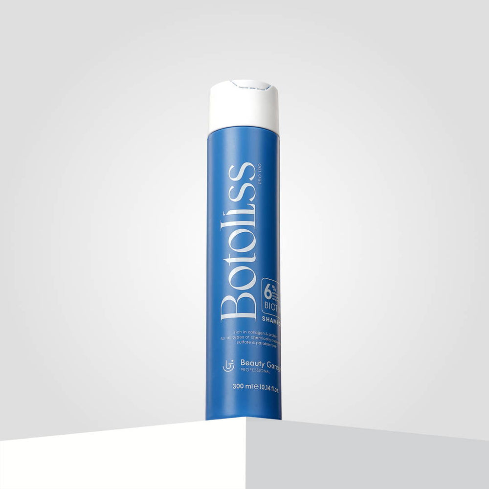 "Botoliss Biotin Shampoo" with a white cap is elegantly placed on a white surface, set against a light gray backdrop.